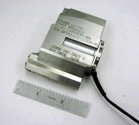 A metal object placed in front of a scale with white background